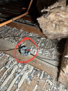Open junction box with unsecured wires in attic floor