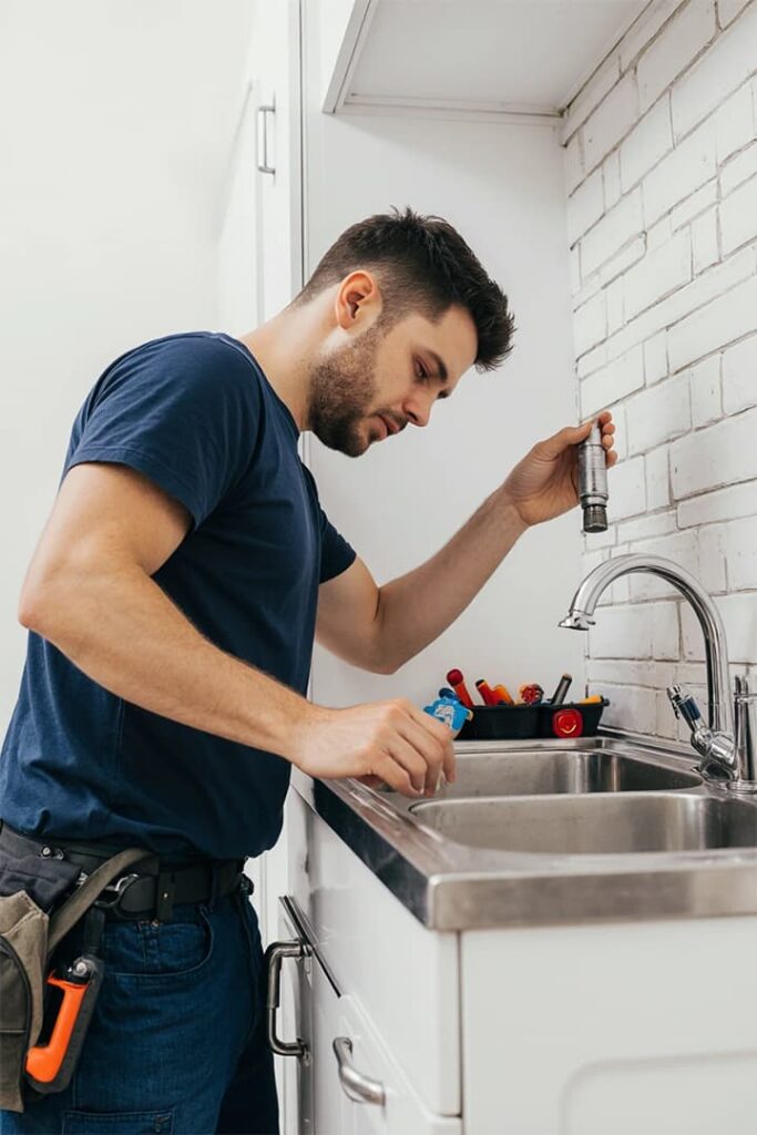 Plumber repairing a kitchen sink in San Francisco home Professional plumber inspecting faucet and fixing kitchen sink in a San Francisco residential apartment