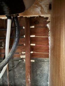 Older knob-and-tube wiring passing through wood studs in an unfinished wall cavity