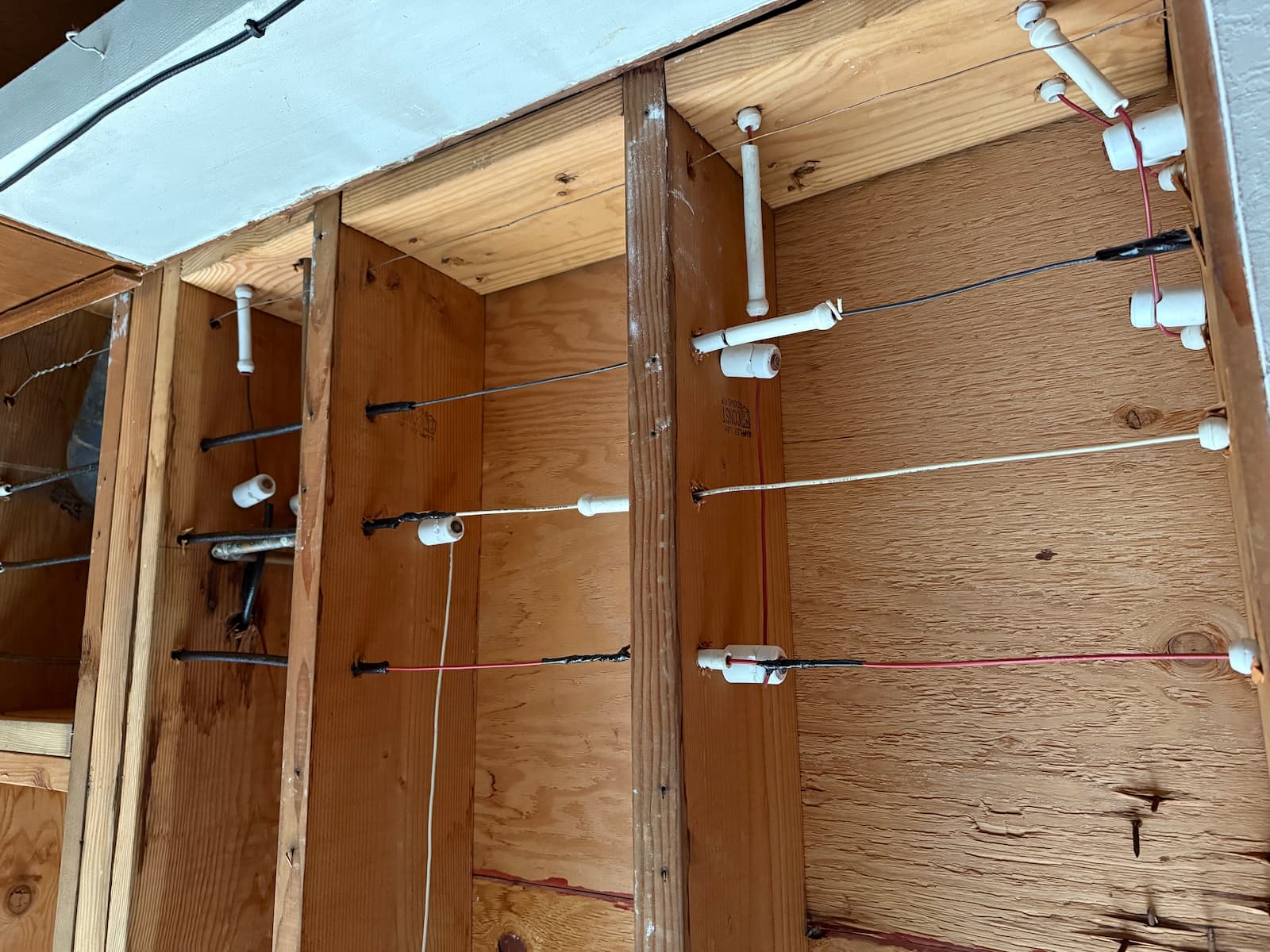 Exposed knob and tube wiring in wall framing during electrical replacement work
