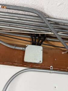 Covered junction box with neatly routed metal conduit along a ceiling beam