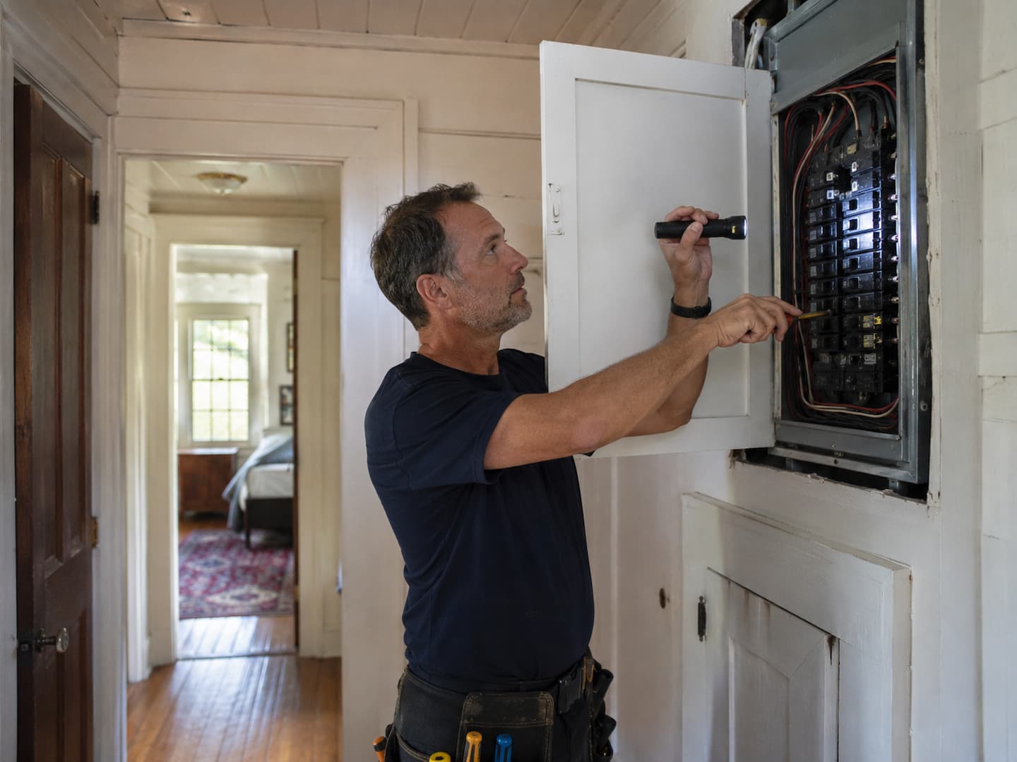 Electrician inspecting an older electrical panel in a Mill Valley home