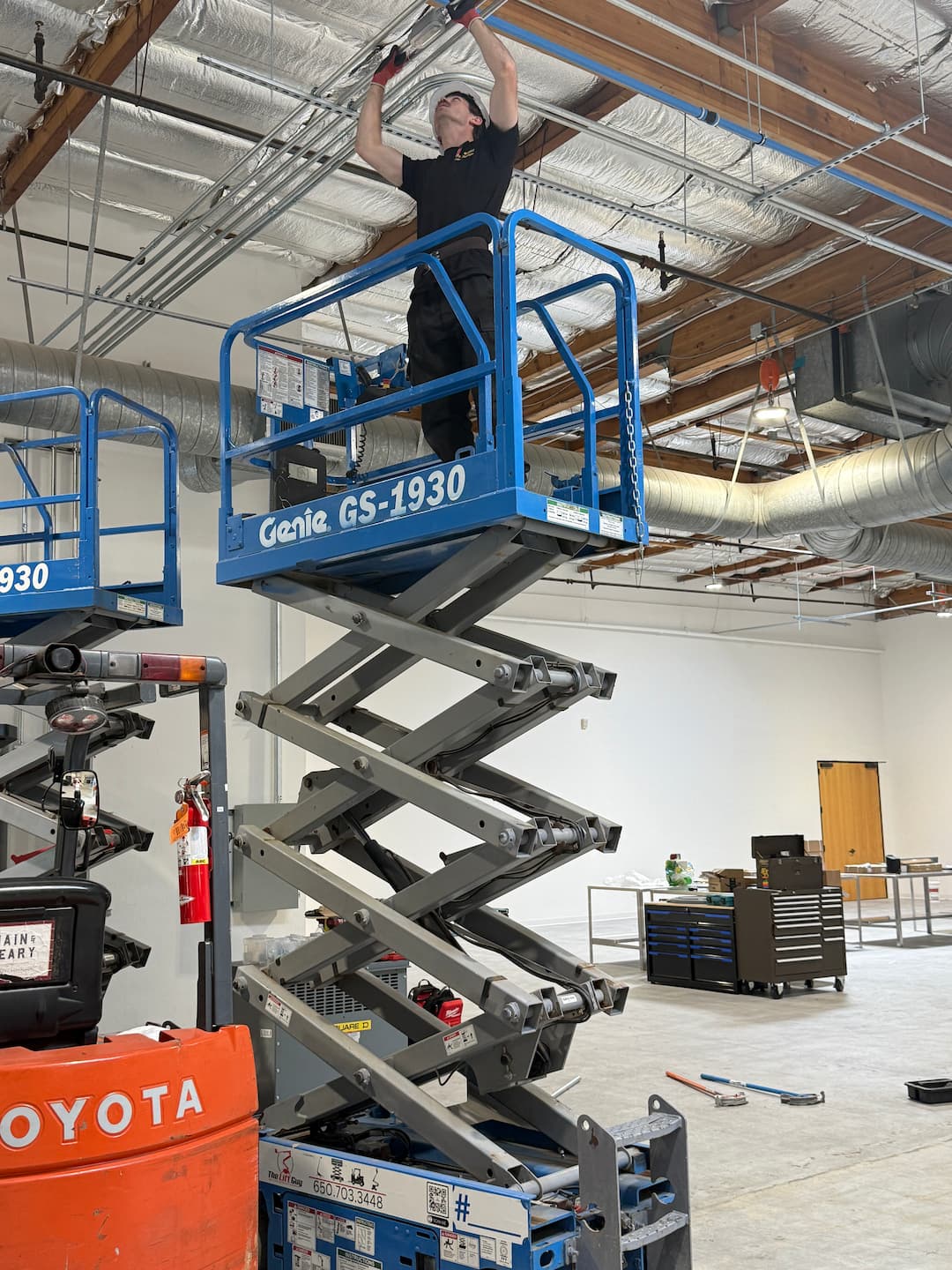 Scissor lift overhead conduit installation in manufacturing facility