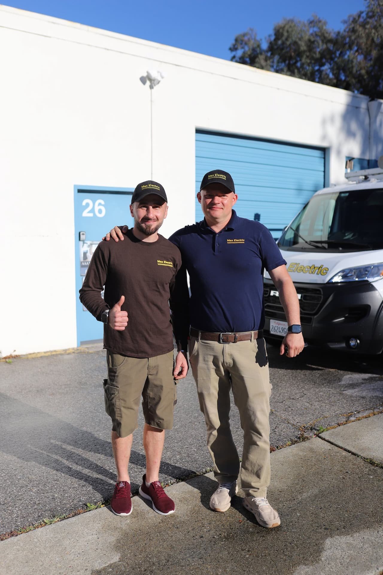 Two MaxElectric electricians beside a branded service van
